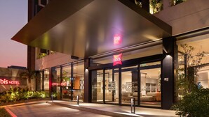 Hotellin sisäänkäynti, jossa on moderni muotoilu, lasiovet ja kyltti, jossa lukee: »ibis HOTEL».