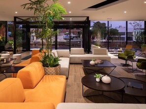 Een moderne zithoek met banken, tafels en potplanten.