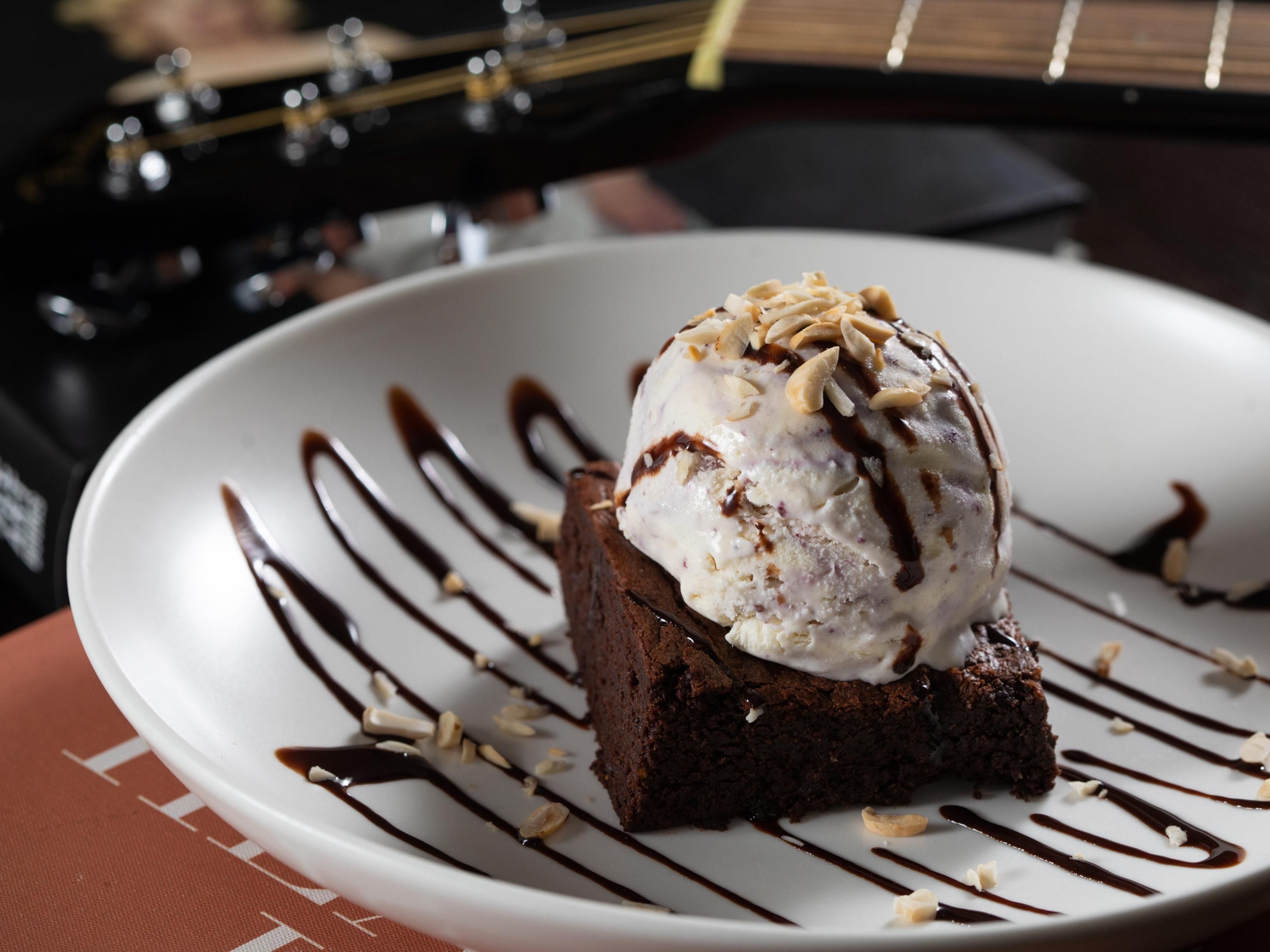 A dessert on a plate with chocolate sauce and almonds.