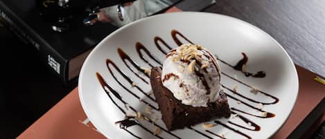 Un dessert su un piatto con salsa al cioccolato e noci, adagiato sopra un libro intitolato “THIS IS”.