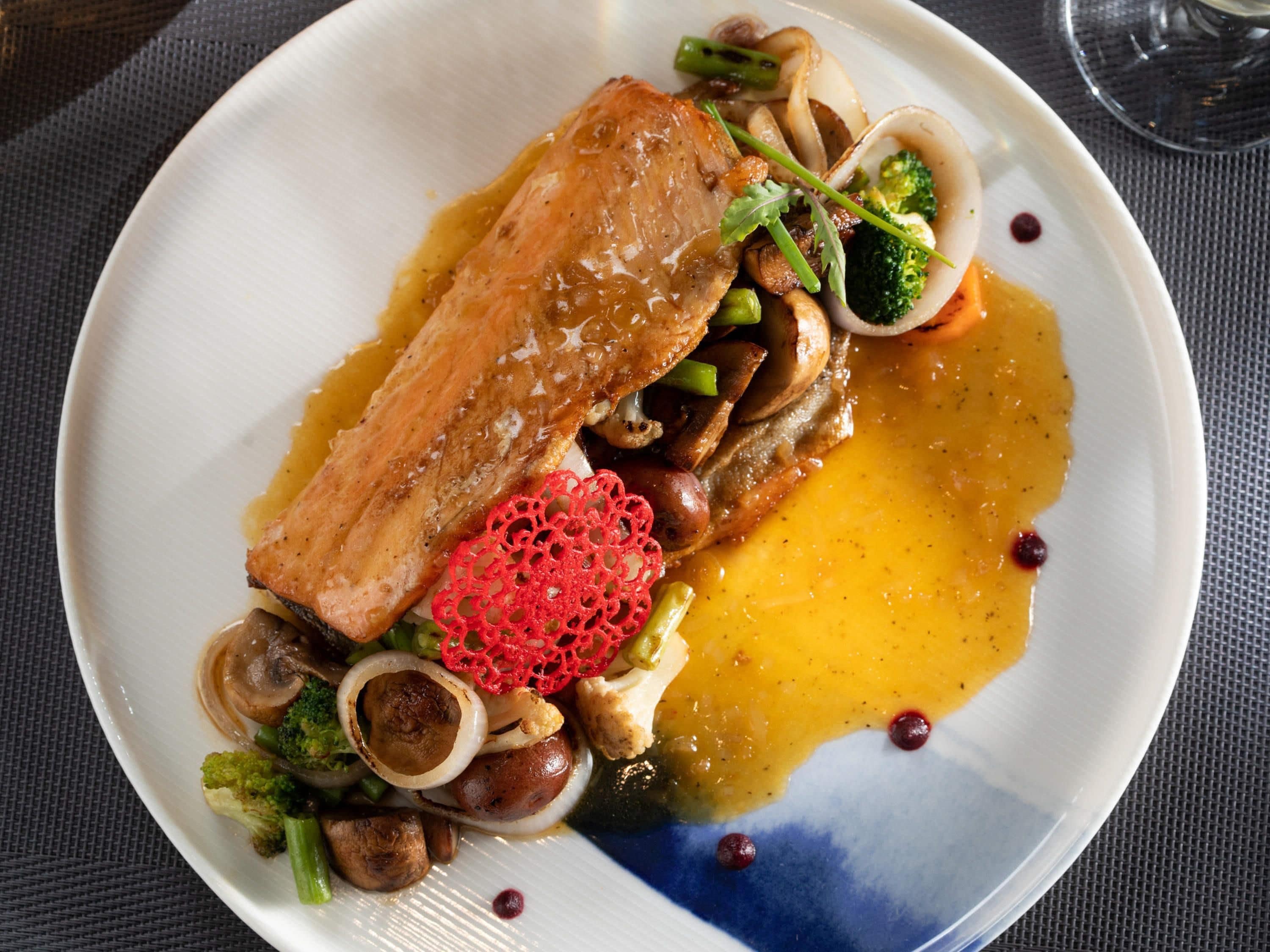 A plate of food with salmon, mushrooms, and vegetables.