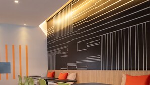 A modern dining area with green chairs, a long table, and a wall with geometric patterns. - Ibis Santa Cruz DE LA Sierra (Santa Cruz)