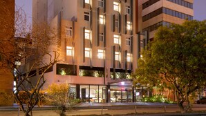 Un hôtel moderne à plusieurs étages, doté de grandes fenêtres et d’une enseigne rouge bien visible sur la façade.