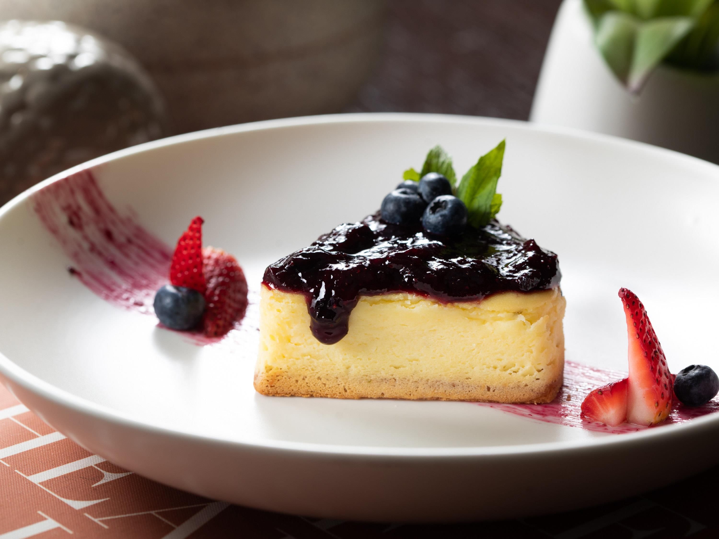 Un postre en un plato blanco, con frutos rojos y una hoja de menta como decoración.