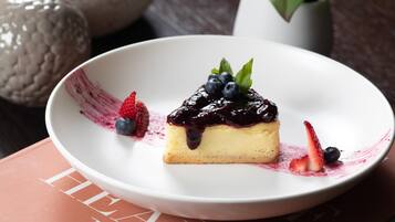 Un postre sobre un plato blanco, con fresas y arándanos al lado.