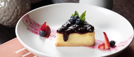 Un postre sobre un plato blanco, con fresas y arándanos al lado.
