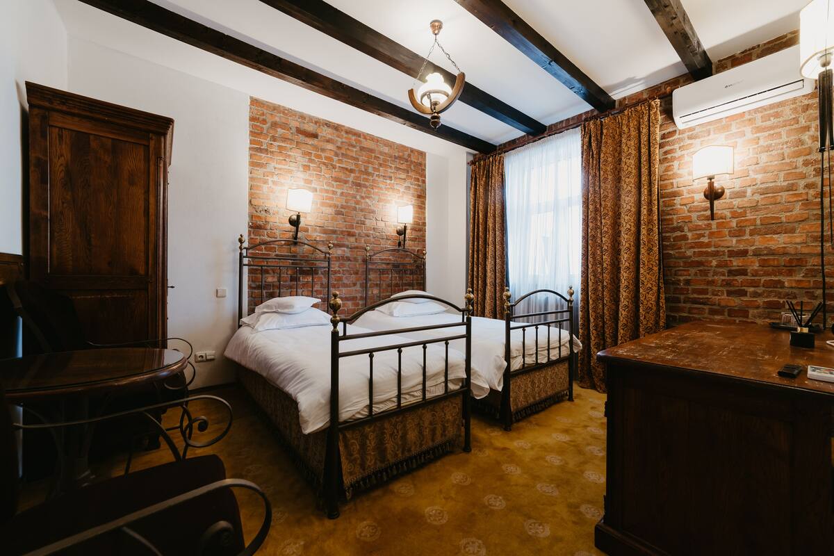 Ein Zimmer mit zwei Betten, einem Holztisch und einer Backsteinwand.
