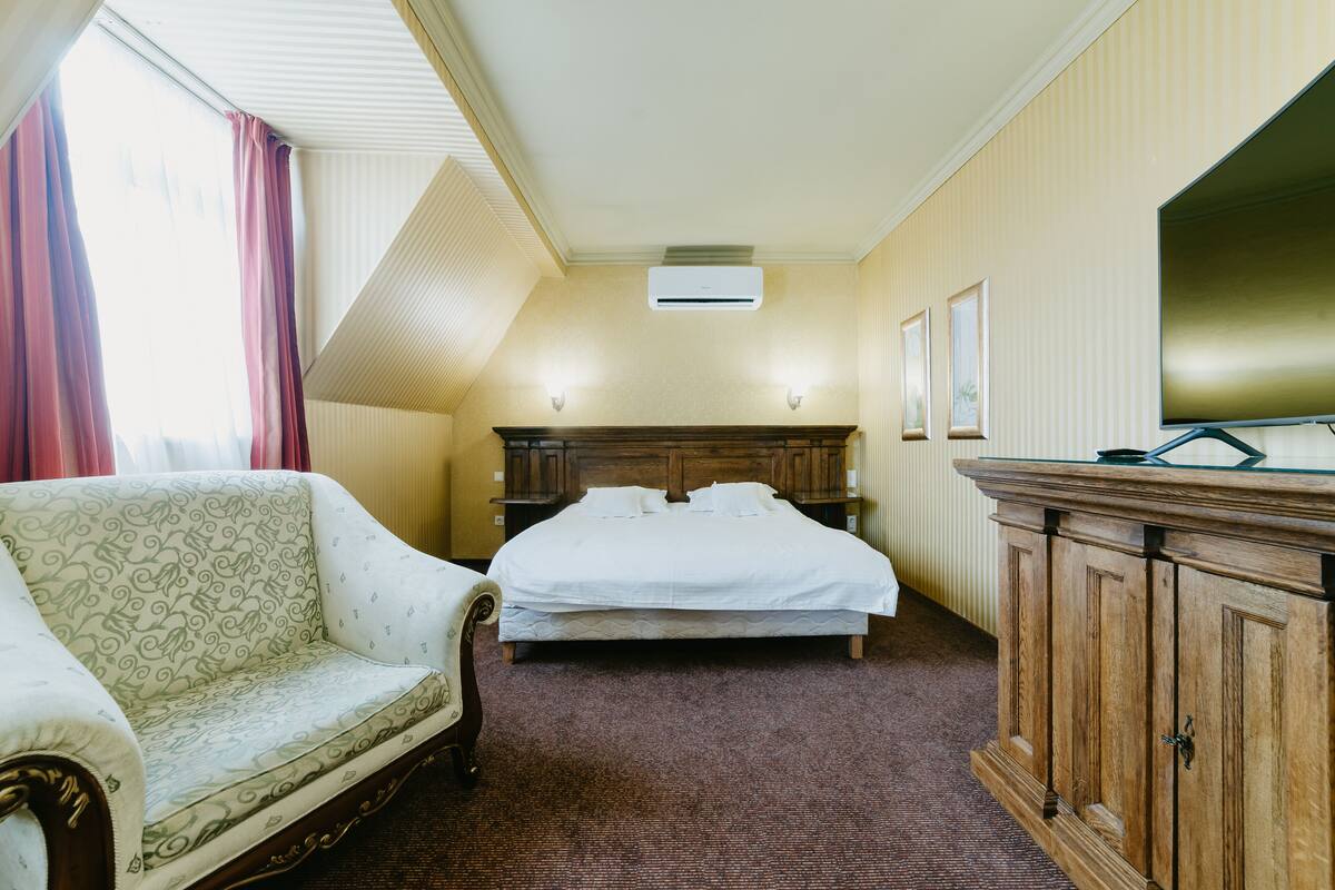 Ein Hotelzimmer mit Bett, Sofa, Holzschrank und Fernseher.