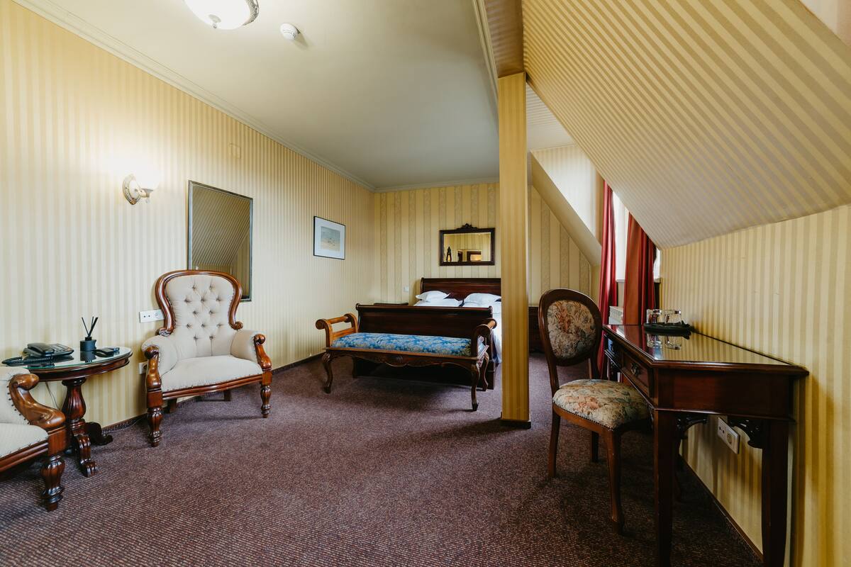 Ein Hotelzimmer mit einem Bett, zwei Sesseln, einem Schreibtisch und einem Spiegel.