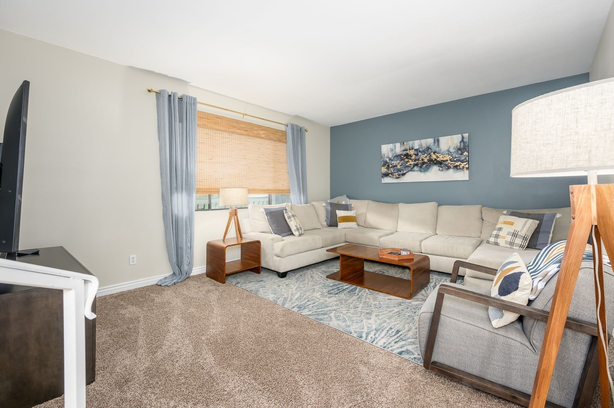 A living room with a sectional sofa, a coffee table, a TV, and a lamp.