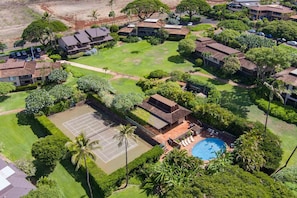 An aerial view of a residential area with multiple houses, a tennis court, and a swimming pool.
