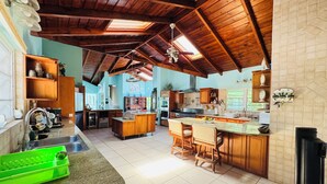 A spacious kitchen with wooden beams, a central island, and a dining area with chairs.