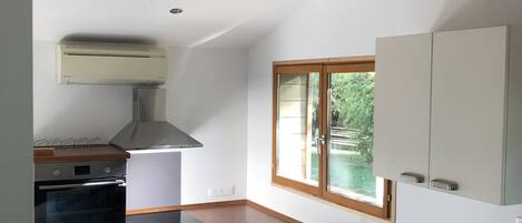Eine kleine Küche mit Backofen, Spüle und Blick auf Grünflächen.