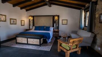 Een slaapkamer met een groot bed, een houten bankje, een stoel en een nachtkastje.