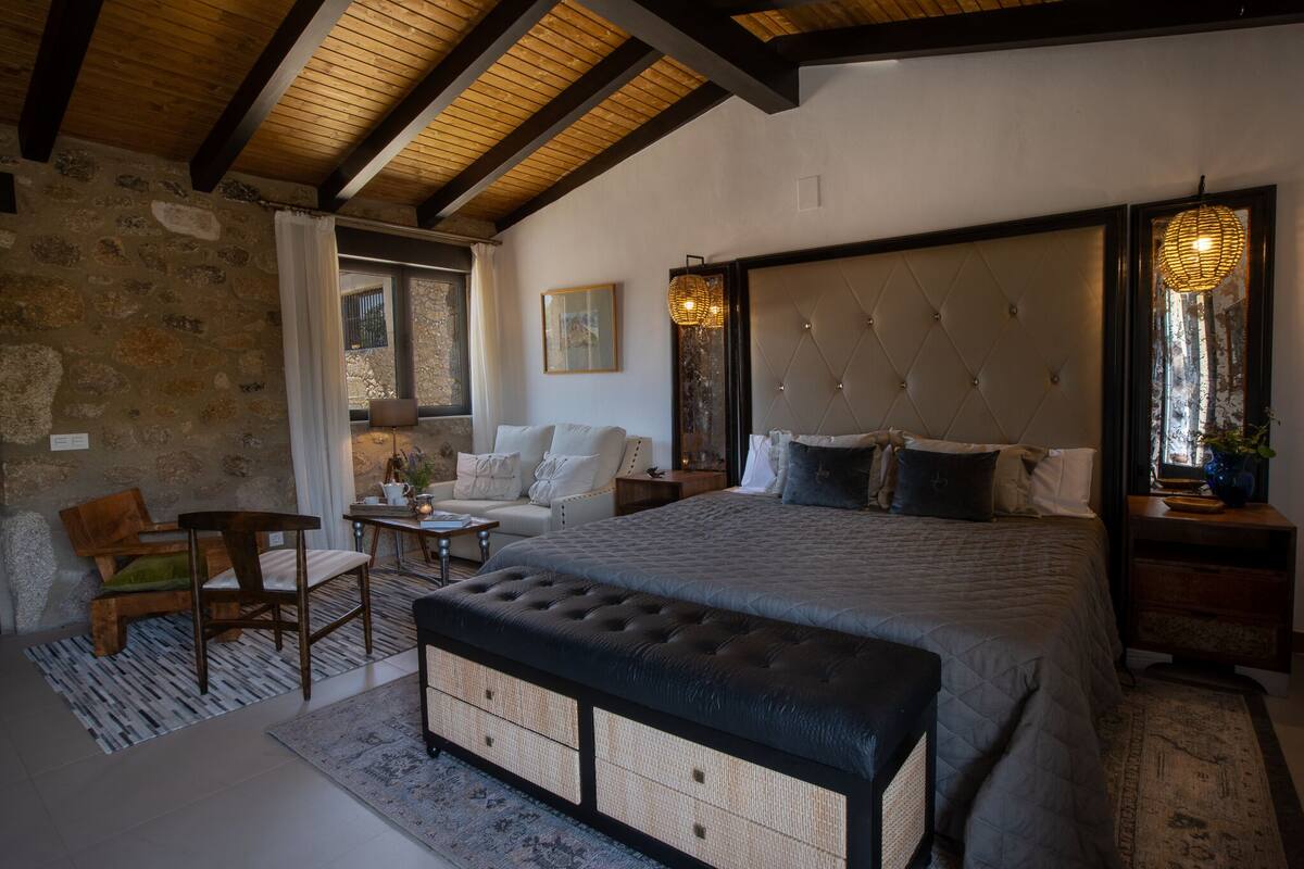 Ein Schlafzimmer mit einem großen Bett, einer Holzbank, einem kleinen Tisch und einem Stuhl.
