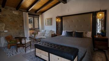 A bedroom with a large bed, a wooden bench, a small table, and a chair.