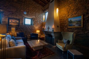 Una sala de estar acogedora con paredes de piedra, chimenea y asientos cómodos.