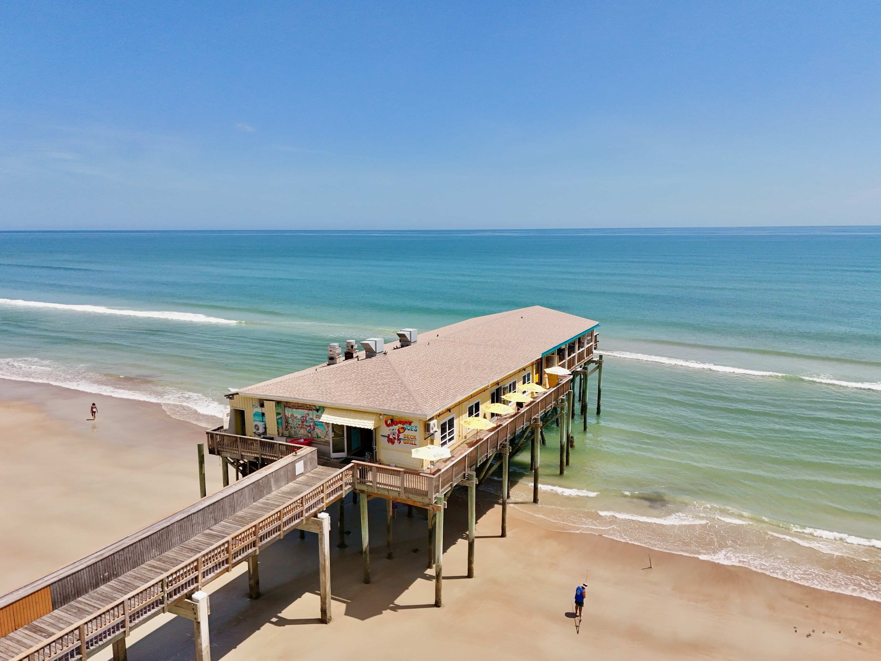Un molo sul lungomare con un ristorante, un pontile di legno e vista sull'oceano.