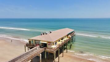 A beachside pier with a restaurant, wooden deck, and ocean view.