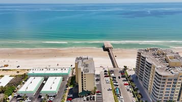 A coastal hotel with a parking lot, a beach, and a pier.