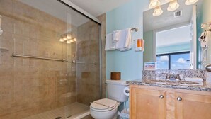 Une salle de bain avec une douche à parois de verre, des toilettes et un meuble-lavabo avec un évier et un miroir.