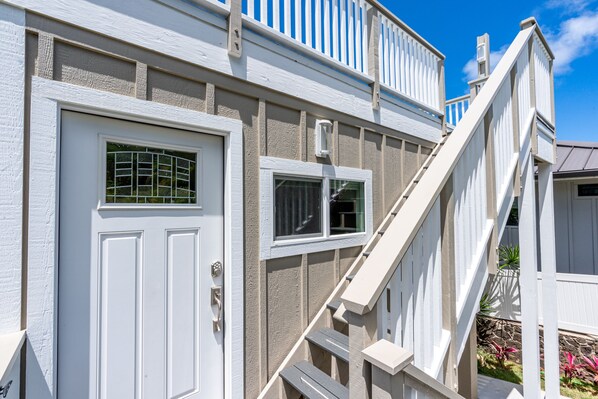 A two-story house with a white exterior, a front door, and a staircase leading to the upper level.
