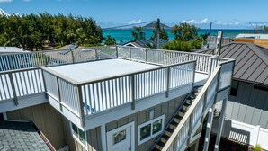 A multi-level residential building with a balcony, a staircase, and a view of the ocean. - Kailua Beach/Lanikai LUX apartment w/Ocean Views from Rooftop Sun Deck (Kailua)