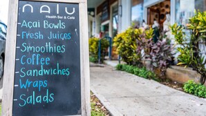 A chalkboard menu outside a health bar and café listing acai bowls, fresh juices, smoothies, coffee, sandwiches, wraps, and salads. - Kailua Beach/Lanikai LUX apartment w/Ocean Views from Rooftop Sun Deck (Kailua)