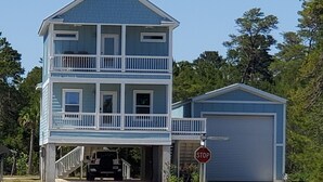 Un immeuble de deux étages doté d’un balcon, d’un garage et d’un panneau de signalisation indiquant un arrêt.