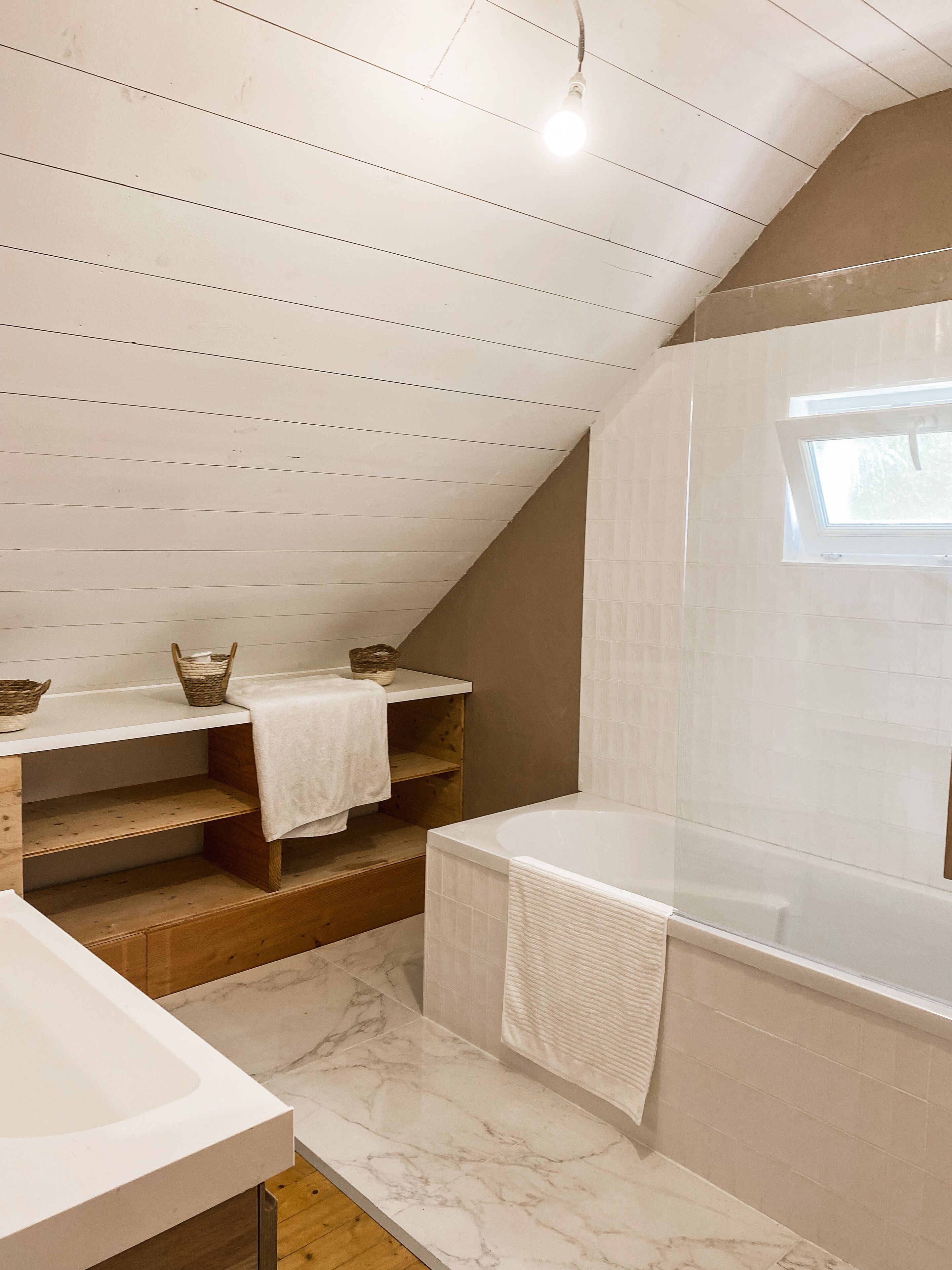Un baño con bañera, lavabo, tocador con repisas y una ventana.