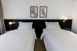 A hotel room with two beds, a patterned wall, and framed artwork above the beds. - Intercity Tatuapé (São Paulo)