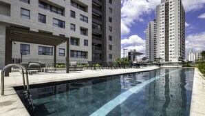A modern hotel with a swimming pool, outdoor seating, and high-rise buildings in the background. - Intercity Tatuapé (São Paulo)