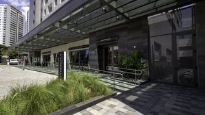 A modern hotel entrance with a covered walkway, a reception desk, and a gated entrance. - Intercity Tatuapé (São Paulo)