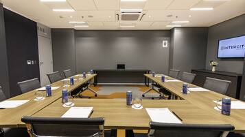 A conference room with a long table, chairs, and a screen displaying the InterCity Hotel name.