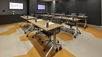 A conference room with multiple tables, chairs, and a large screen displaying the Intercity Hotels logo.