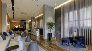 A modern lobby with a seating area, a reception desk, and a staircase leading to an upper level. - Intercity Tatuapé (São Paulo)