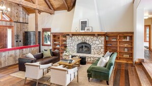 Ein geräumiges Wohnzimmer mit Kamin aus Stein, Holzbalken und hohen Decken.