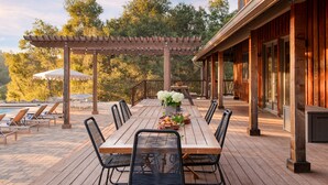 Eine Terrasse im Freien mit einem Holztisch, Stühlen und einer Pergola.