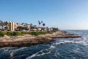 A coastal town with buildings along the beach, rocky shoreline, and waves crashing onto the shore. - Oceanfront in La Jolla, Steps to Beach, Shops, Dining | Dawn Patrol by AvantStay (La Jolla)