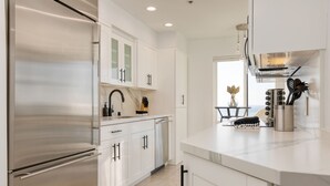 A modern kitchen with white cabinets, stainless steel appliances, and a marble countertop. - Oceanfront in La Jolla, Steps to Beach, Shops, Dining | Dawn Patrol by AvantStay (La Jolla)