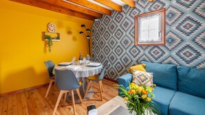 Un espace repas doté d’un plafond en bois, d’un mur orné de motifs et d’un canapé bleu agrémenté de coussins.