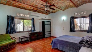 Une pièce comprenant un lit, un canapé vert, une commode et une armoire.