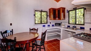 Une cuisine compacte avec un coin repas, comprenant une table ronde en bois, des chaises et une cuisinière.