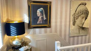 A staircase with a lamp, framed artwork, and a bust sculpture.