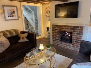 A living room with a fireplace, a sofa, a coffee table, and a TV mounted on the wall.
