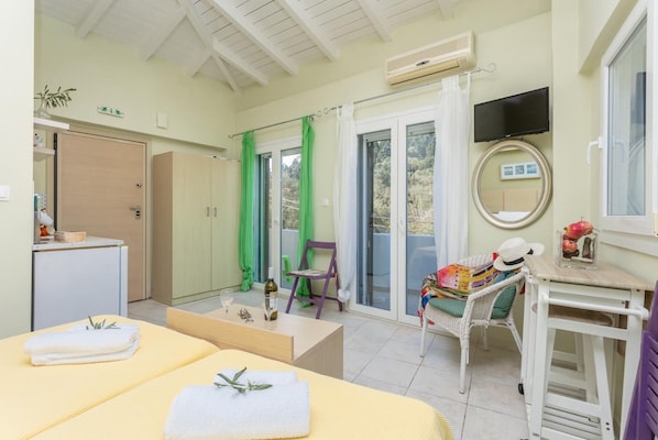 A room with a bed, a chair, a table, a TV, and a sliding glass door to the outside.