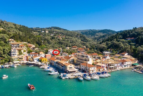 A coastal town with buildings along the waterfront, boats docked, and a hilly backdrop.