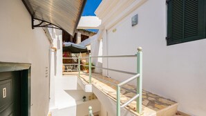 A narrow outdoor corridor with a metal staircase leading to a covered patio area. - Niki Studio Tria - One Bedroom Apartment, Sleeps 2 (Lakka)