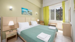 A hotel room with a bed, bedside tables, a nightstand, a window with curtains, and a painting on the wall. - Niki Studio Tria - One Bedroom Apartment, Sleeps 2 (Lakka)