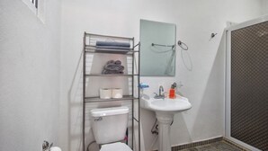 Ein Badezimmer mit Toilette, Waschbecken, Handtuchhalter und Duschbereich.